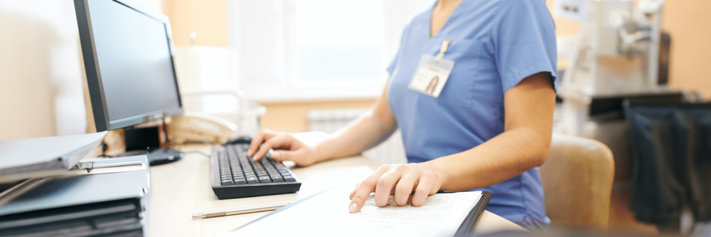 Nursing using computer and reading from notes 