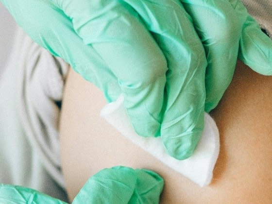 Healthcare professional applying cotton pad on patient’s arm